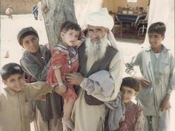 Ein afghanischer Mann mit langem Bart ist umringt von vielen Kindern