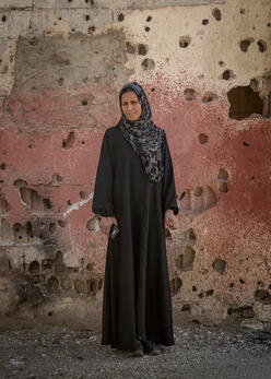 Frau steht in Syrien vor einer Wand
