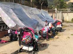Venezolaner*innen nutzen Planen und Kinderwagen, um Sonnenschutz aufzubauen
