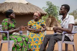 Zwei Frauen sprechen mit einem Mann in Uganda. 