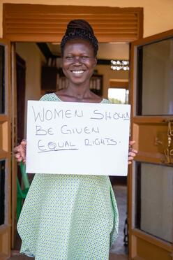 Grace hält ein Schild auf dem "Women should be given equal rights" steht.