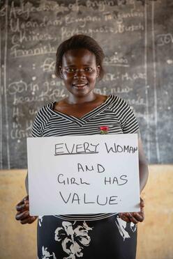 Jackie hält ein Schild auf dem steht "Every woman and girl has value".
