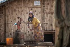 Eine Frau pumpt Wasser in Myanmar.