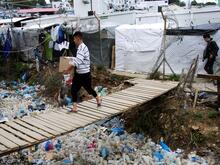 Ein Mann trägt eine Kiste über eine Brücke im Flüchtlingslager Moria