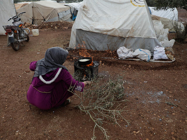 Eine geflüchtete Frau kocht in einem Flüchtlingslager in Idlib