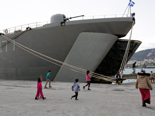 Kinder laufen am Hafen vor Kriegsschiff in Lesbos