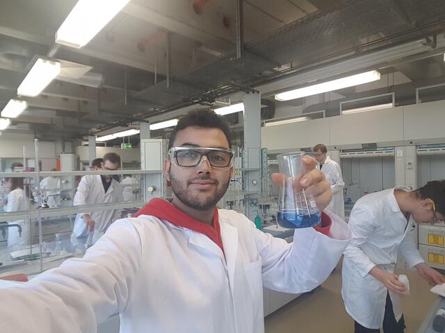 Zain im weißen Kittel im Chemielabor der Hochschule