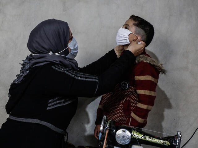 Syrische Mutter setzt ihrem Sohn eine Alltagsmaske auf