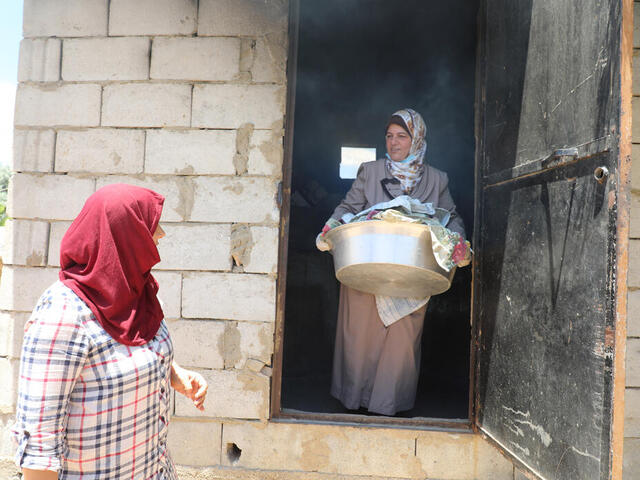 Syrische Krankenschwester und Freiwillige Mariam trägt medizinische Hilfsgüter aus einem Gebäude, während sie mit einer anderen Frau vor der Tür spricht 