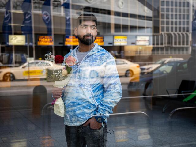 Mehdi am Flughafen hinter einer Scheibe. 