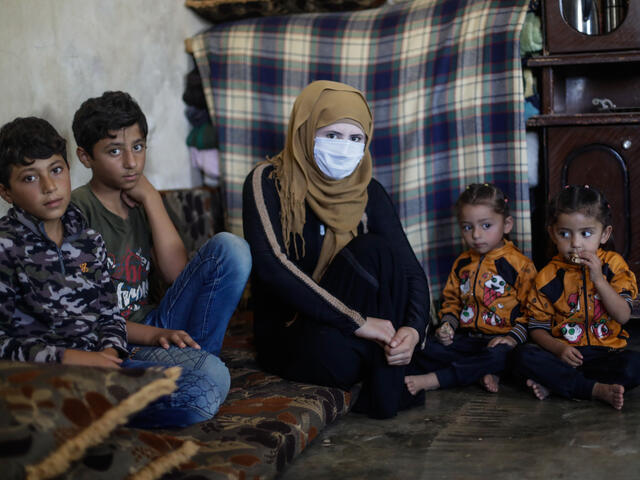 Eine syrische Mutter sitzt mit ihren 5 Kindern auf einer kleinen Matratze