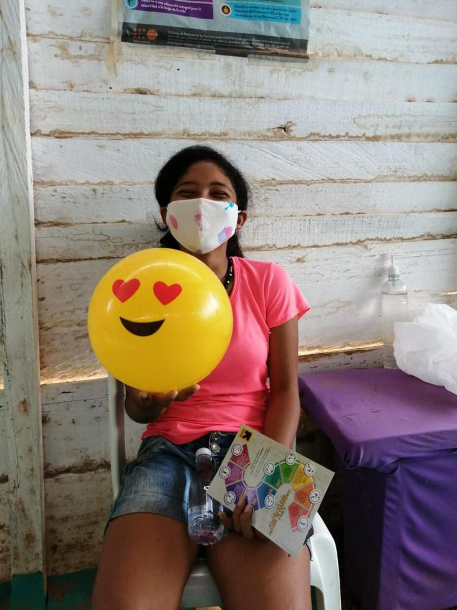 Ein Mädchen mit einem Luftballon schaut fröhlich in die Kamera.
