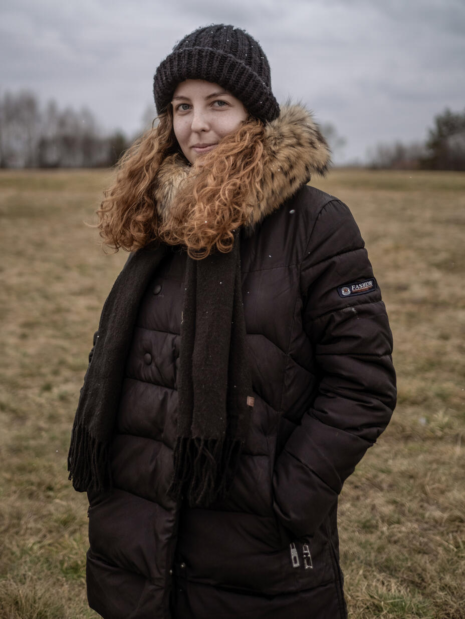 Anastasia steht auf einem Feld an der polnisch-ukrainischen Grenze und schaut in die Kamera