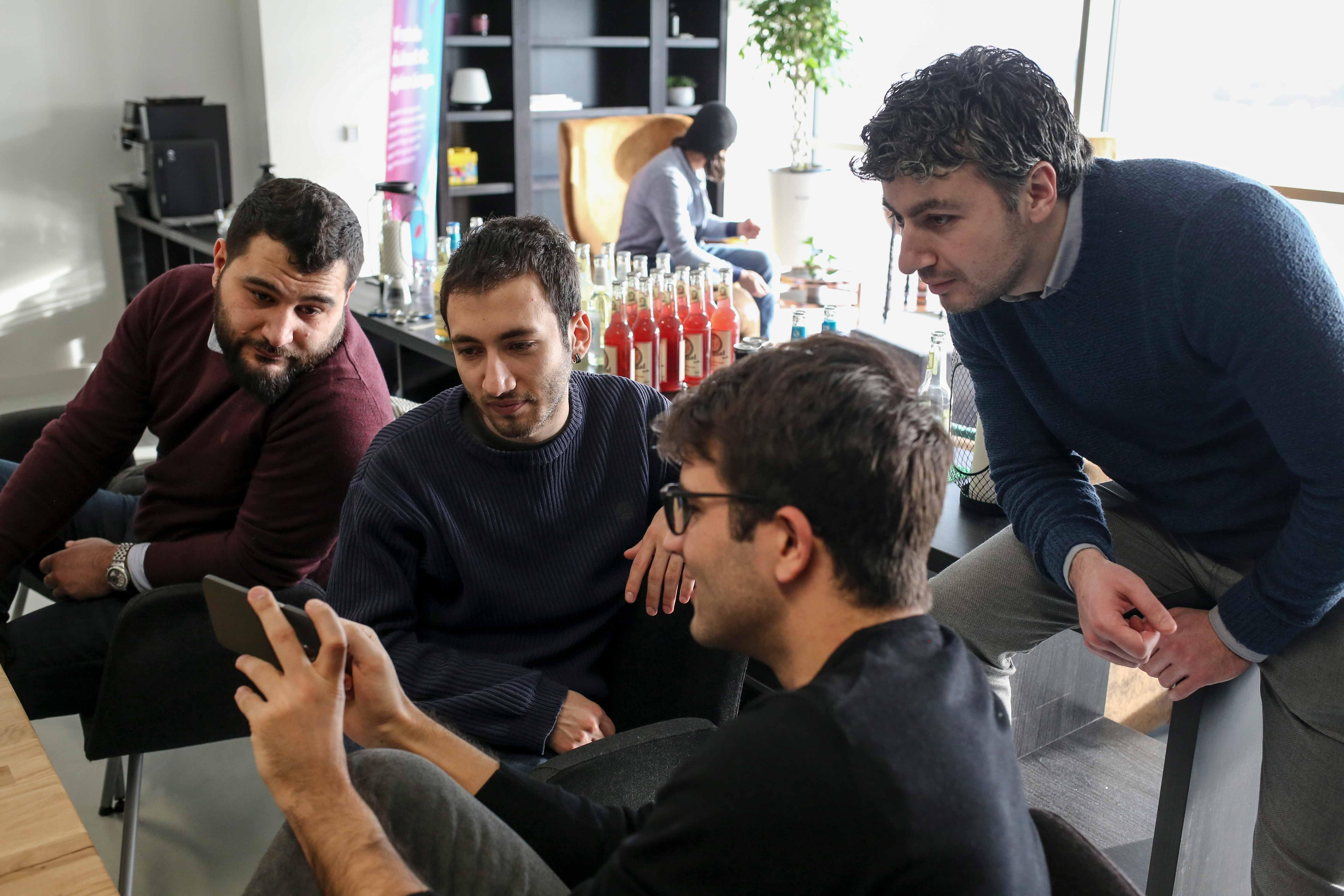 Männliche Teilnehmer des Devugee-Programms in Berlin unterhalten sich.