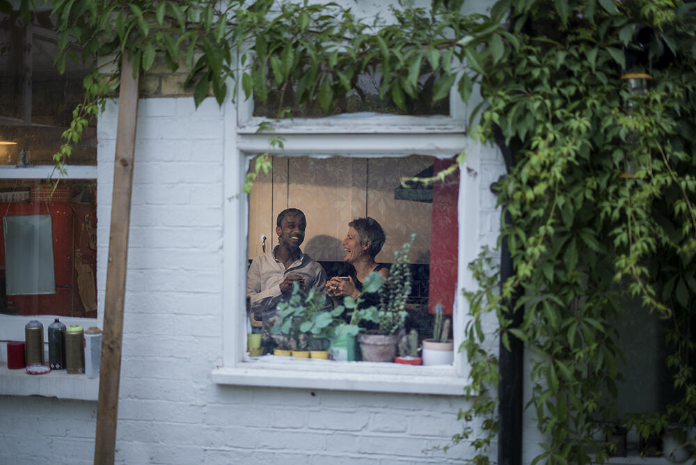 Ein Mann und eine Frau sitzen auf einer Couch durch ein Fenster fotografiert