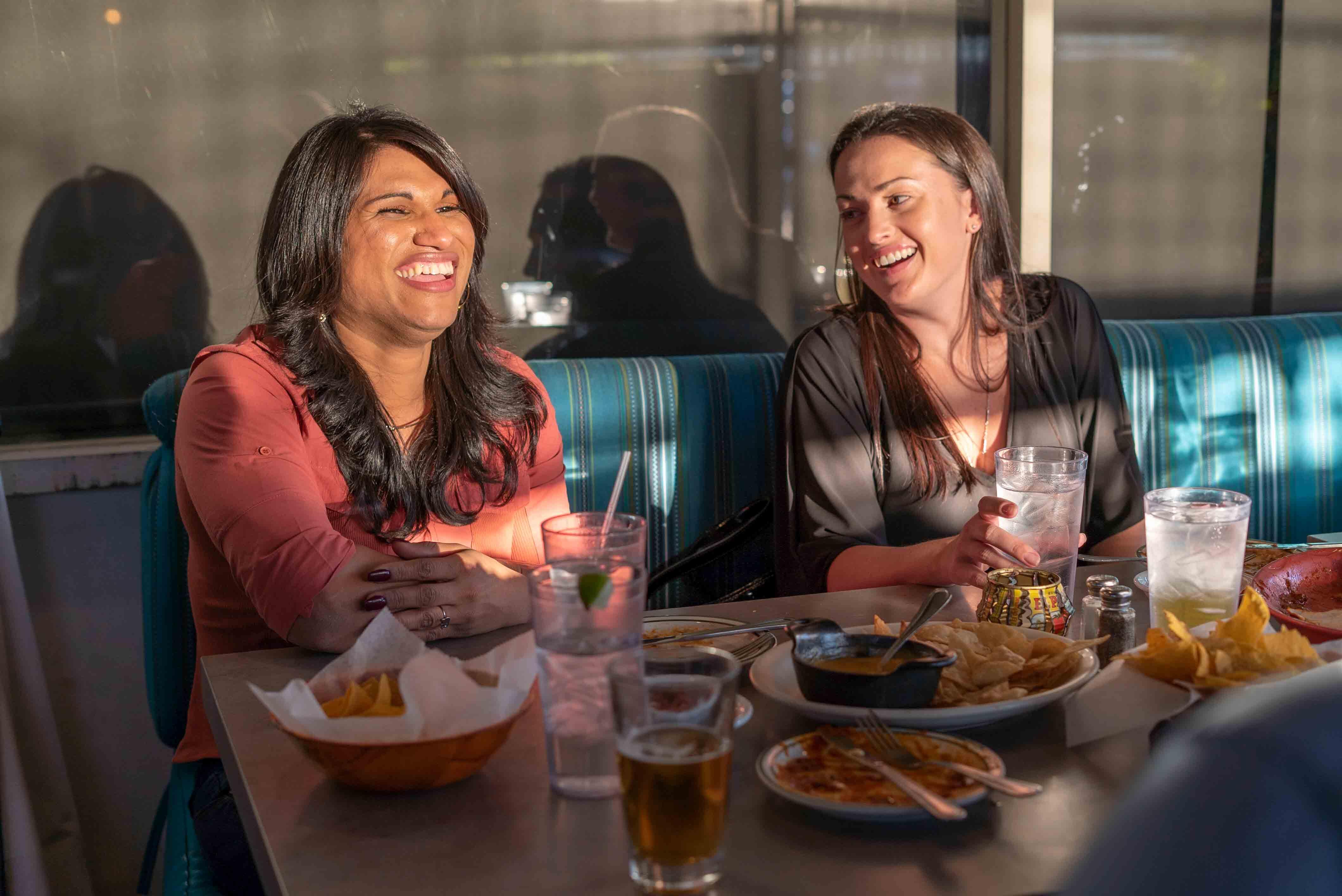 Zwei Frauen sitzen in einem Cafe und lachen herzlich in Phoenix, Arizona
