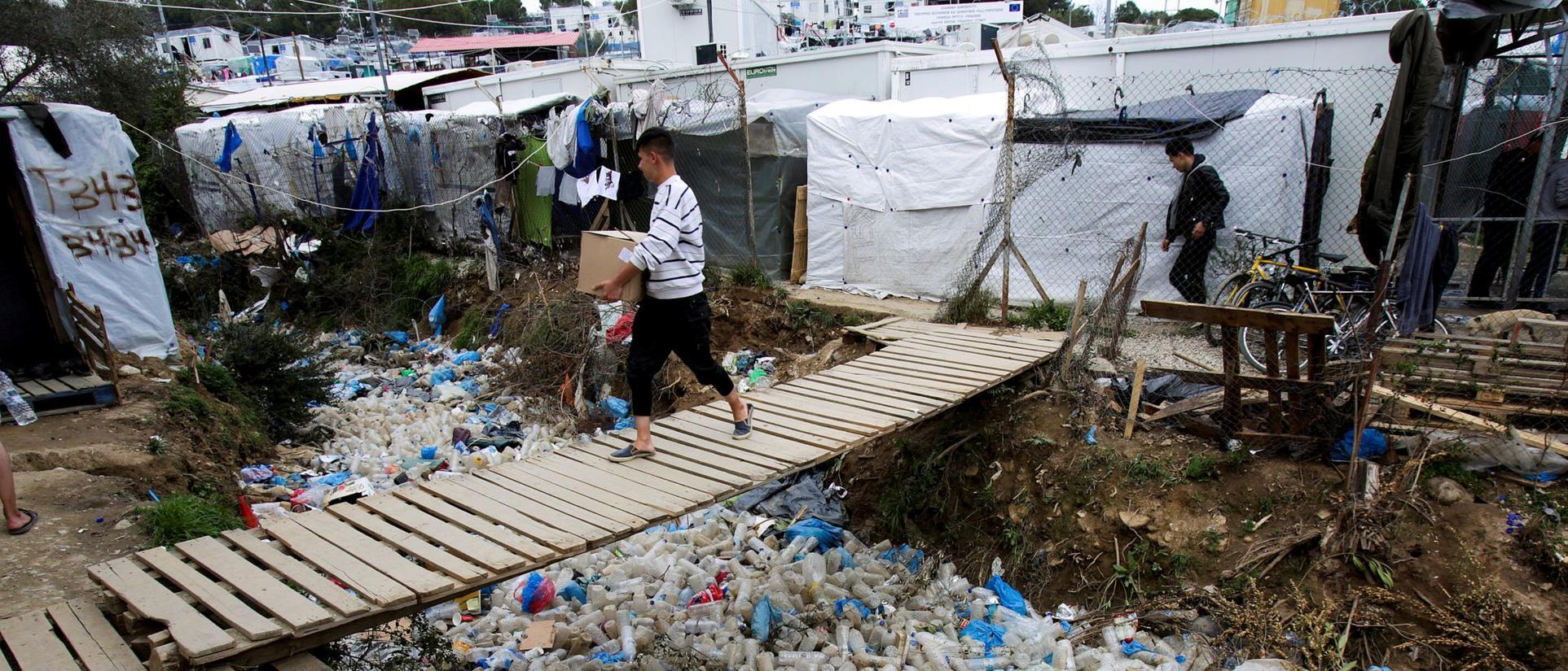 Ein Mann trägt eine Kiste über eine Brücke im Flüchtlingslager Moria