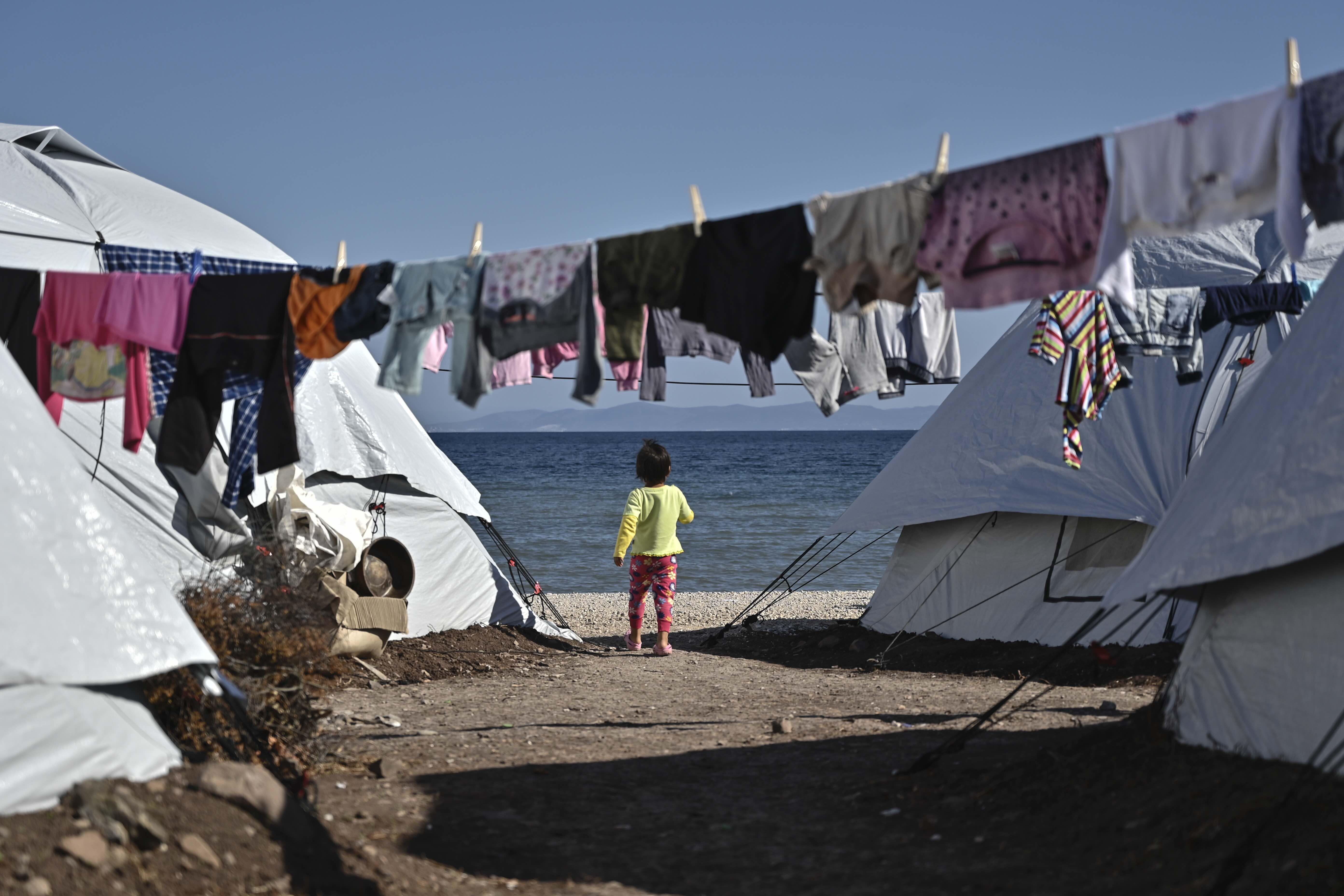 Child stands between tents at the new Lesvos camp