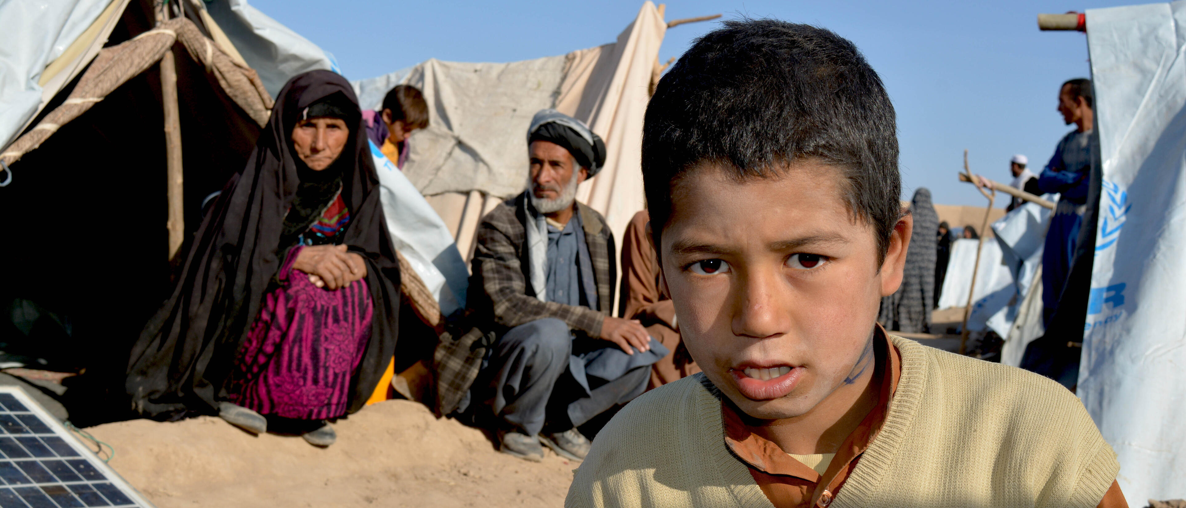 En familj på flykt i Herat, Afghanistan. Pojke tittar in i kameran.