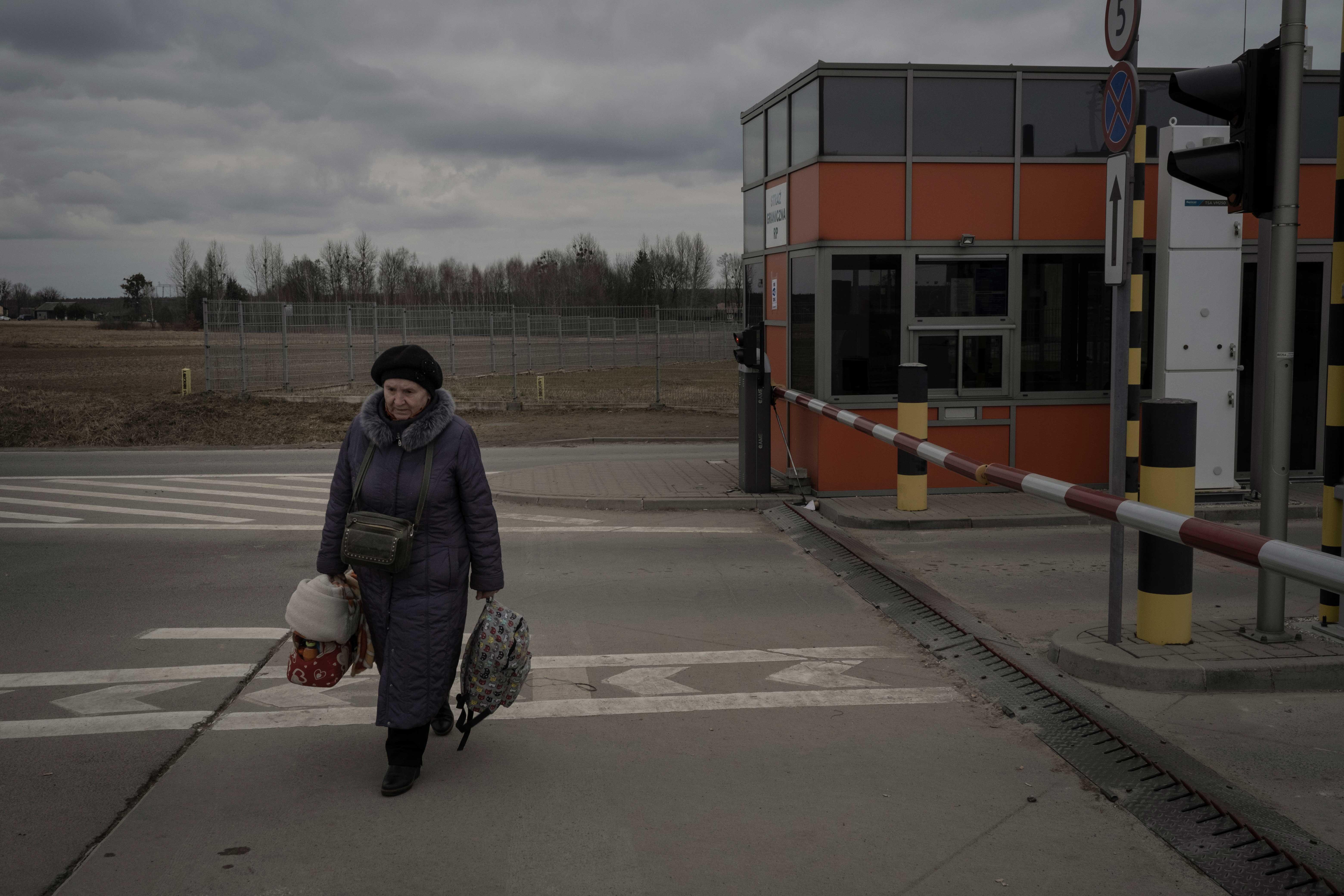 Frau mit Taschen läuft an einem Grenzübergang an der polnisch-ukrainischen Grenze entlang