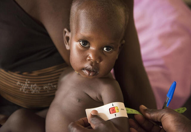 Einem kleinen Kind aus dem Südsudan wird der Arm vermessen