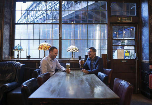 Zwei Männer sitzen an einem Tisch in einem Pub.