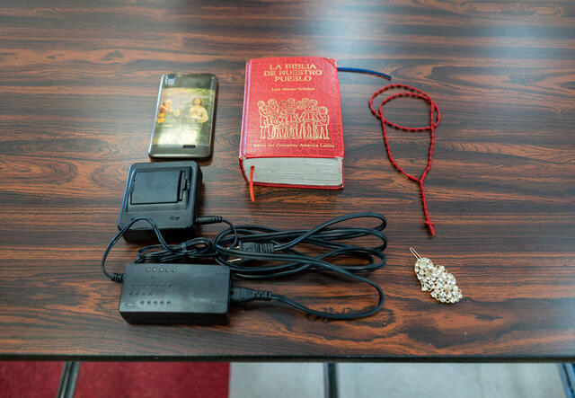 Auf einem braunen Holztisch liegen Elisas Habseligkeiten, eine Bibel, ein Rosenkranz,ihr Handy, ein Ladekabel und eine Haarspange
