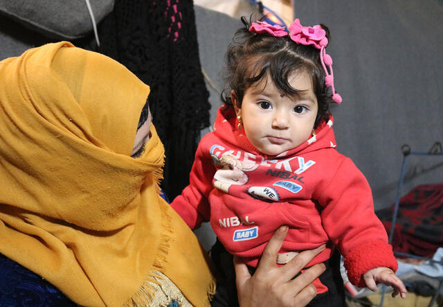 Mutter hält ihr Baby im Areesha Flüchtlingslager, Syrien