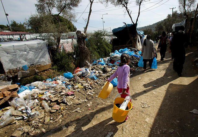 Mädchen läuft mit Eimer durch Flüchtlingslager in Griechenland