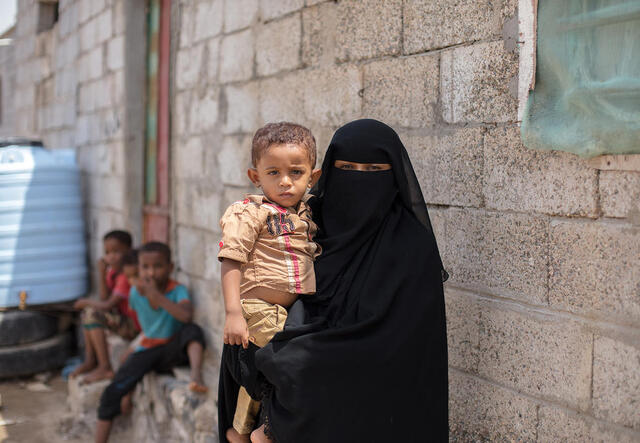 Jemenitische Mutter vor einem Haus mit Kleinkind