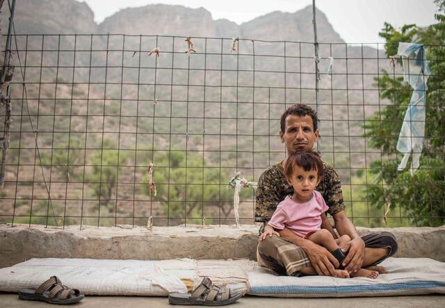 Abdul Ghafar und sein Sohn sitzen auf dem Boden in ihrem Dorf im Süden Jemens,