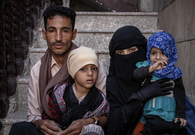 Taqwa und Mohammed sitzen zusammen mit ihren Kindern auf einer Treppe