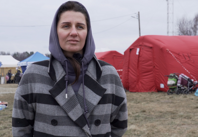 Angelina steht vor einigen Zelten an der polnisch-ukrainischen Grenze