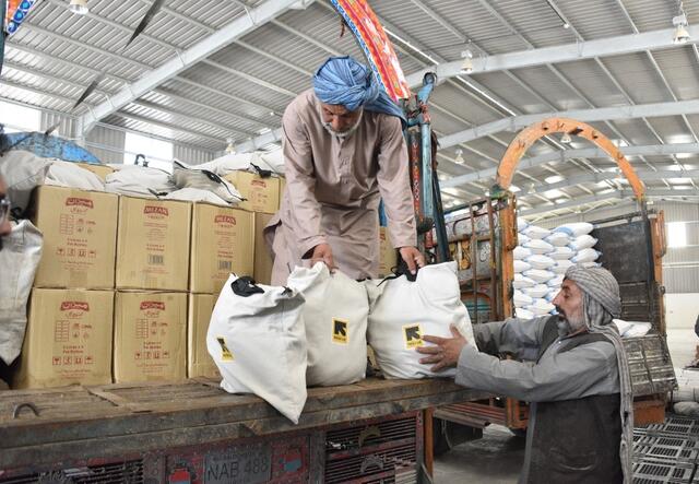 IRC-Helfer laden Säcke mit Lebensmitteln auf Lastwagen.