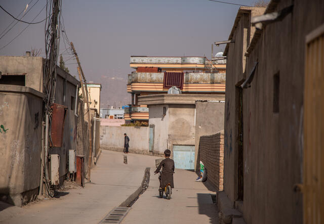 Ein Junge fährt mit dem Fahrrad durch eine Gasse in Afghanistan