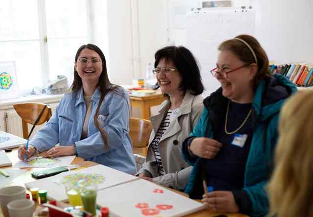 Alina, ihre Mutter Irina und ihre Freundin Switlana Lys lachen gemeinsam bei einer psychologischen Beratung für ukrainische Flüchtlinge. Die Sitzung ist Teil des Projekts "Anknüpfen", das Berufsbildungs- und Integrationsworkshops für Flüchtlinge aus der Ukraine anbietet. 