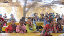 Kinder sitzen in einem Klassenraum, welcher in einem Zelt ist