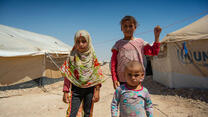 Zwei Mädchen und ein Kleinkind stehen zwischen zwei Zelten der UN in einem Flüchtingslager in Syrien.