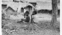 Angolan refugee children sit on the ground outside a row of houses in Zaire.