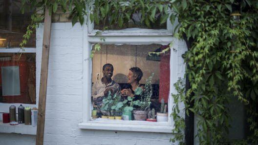 Ein Mann und eine Frau sitzen auf einer Couch durch ein Fenster fotografiert