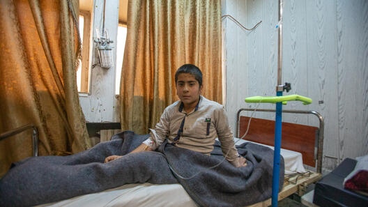 Pojke sitter på en sjukhussäng i Syrien