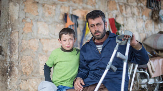 Ein Junge und sein Vater schauen in die Kamera in Syrien.