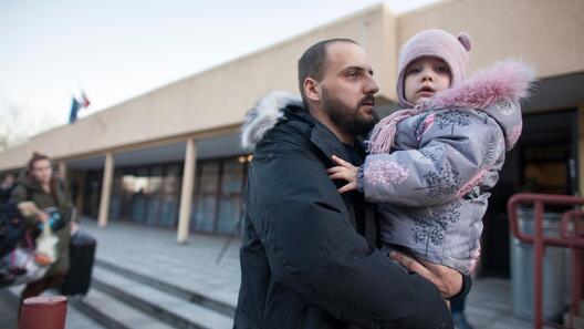 Ein Vater aus der Ukraine hält seine Tochter im Arm und ist auf der Flucht