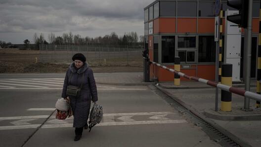 Frau mit Taschen läuft an einem Grenzübergang an der polnisch-ukrainischen Grenze entlang
